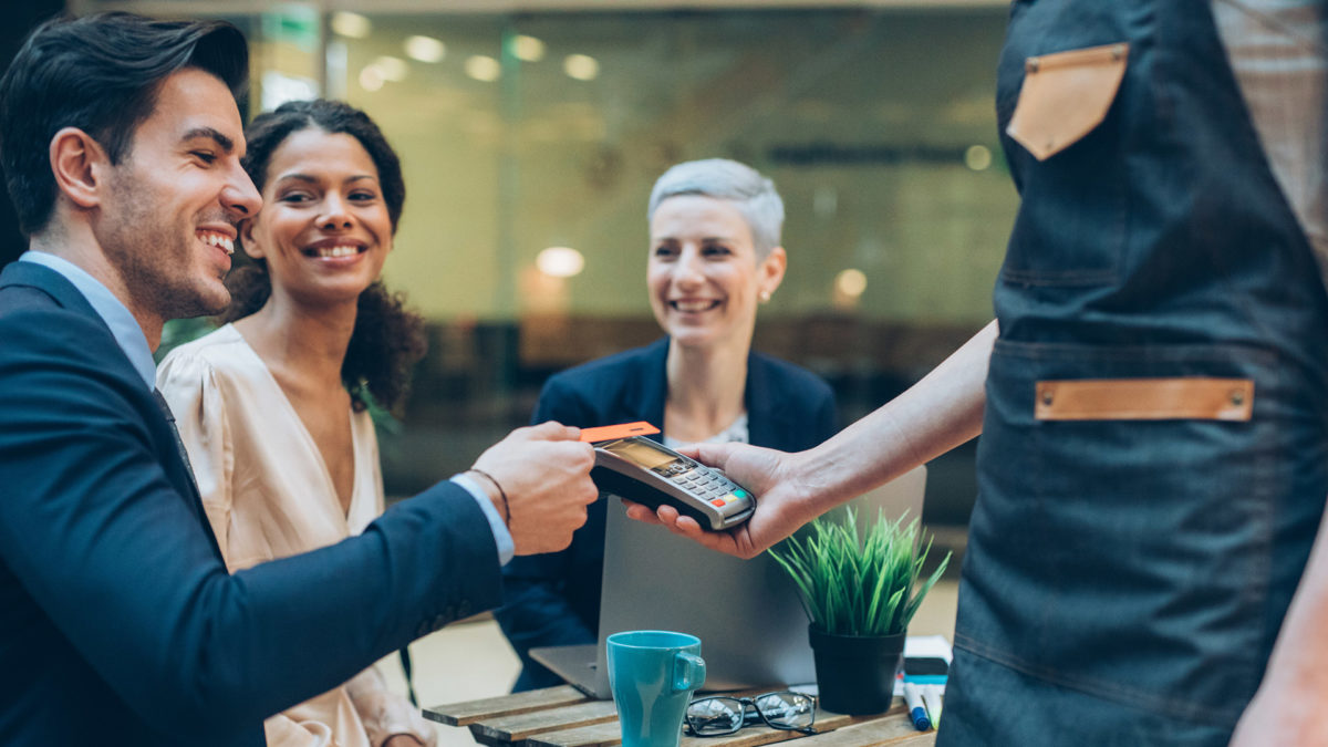 A businessman paying for a meal with two colleagues.